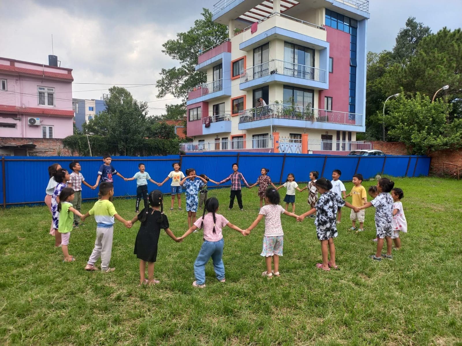The whole class holding hands in one big circle on the green