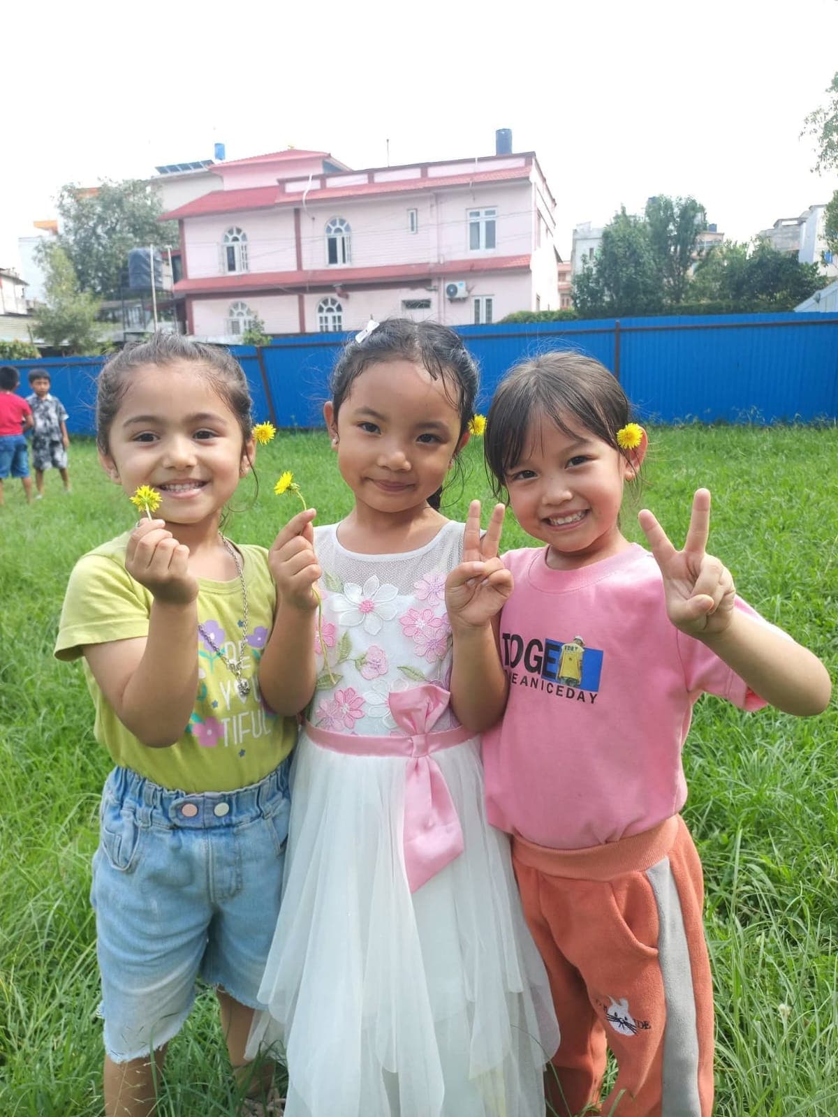 Three smiling friends in the meadow holding little yellow flowers