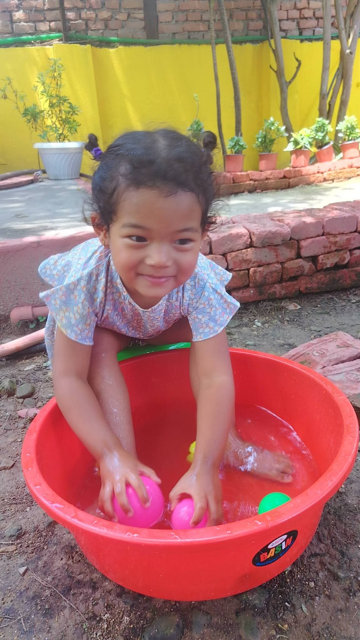 A young learner playing in a tub of water